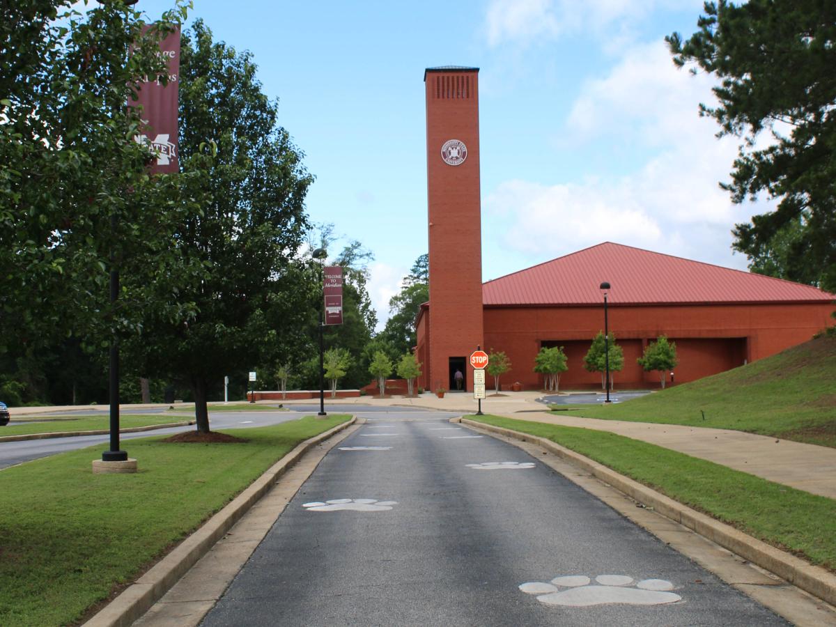 College Park Campus entrance with white paw prints painted on drive toward red brick building.